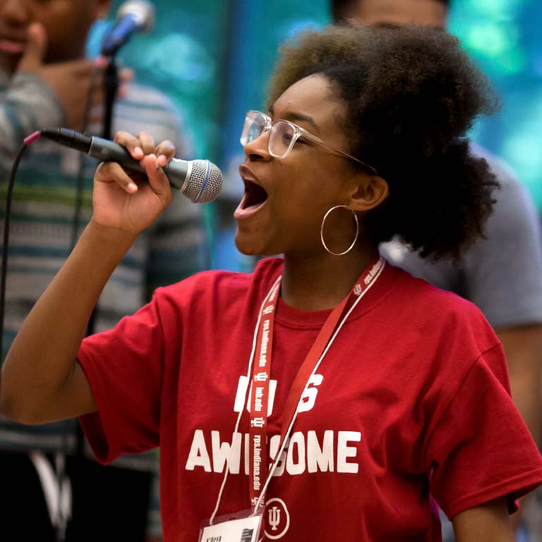 An IU student sings in a microphone. 