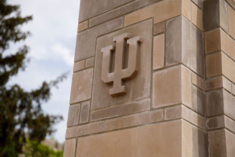 A limestone IU trident adorns a gate outside the Indiana Memorial Union on a summer day at IU Bloomington on Friday, May 17, 2019.