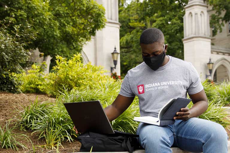 Student with laptop by Sample Gates studying. 