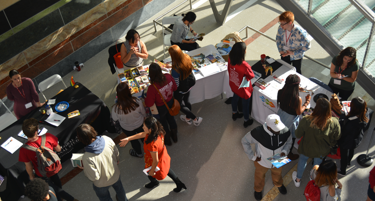 Aerial view of student visiting information tables at the OVPDEMA Study Abroad Fair.