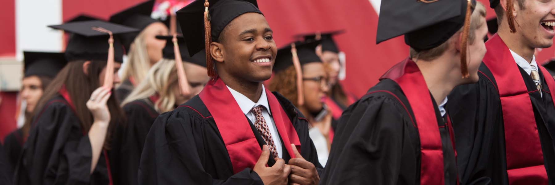 Students talk and smile during a graduation ceremony. 