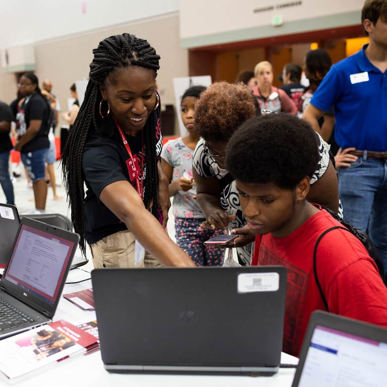 An IU representative helps a student update their 21st Century Scholar information on a laptop computer.