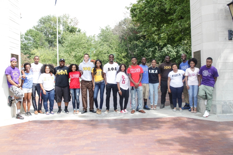 Members of historically black fraternities and sororities stand under the IU Sample Gates.