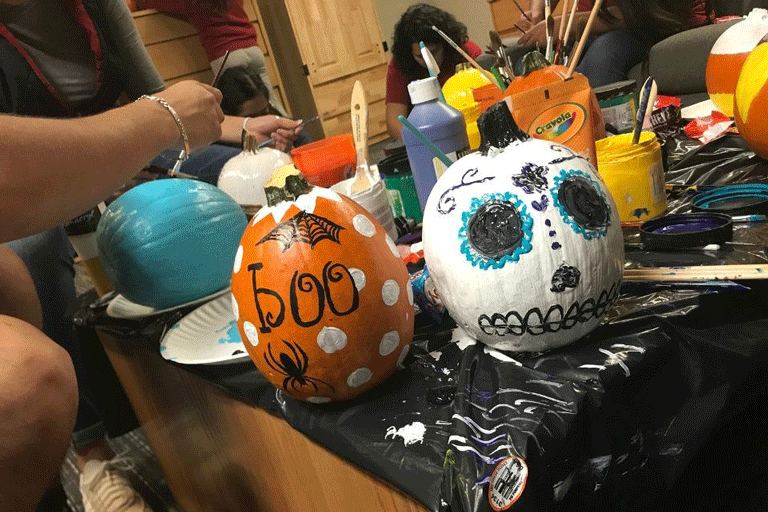 Students painting pumpkins for the Day of the Dead